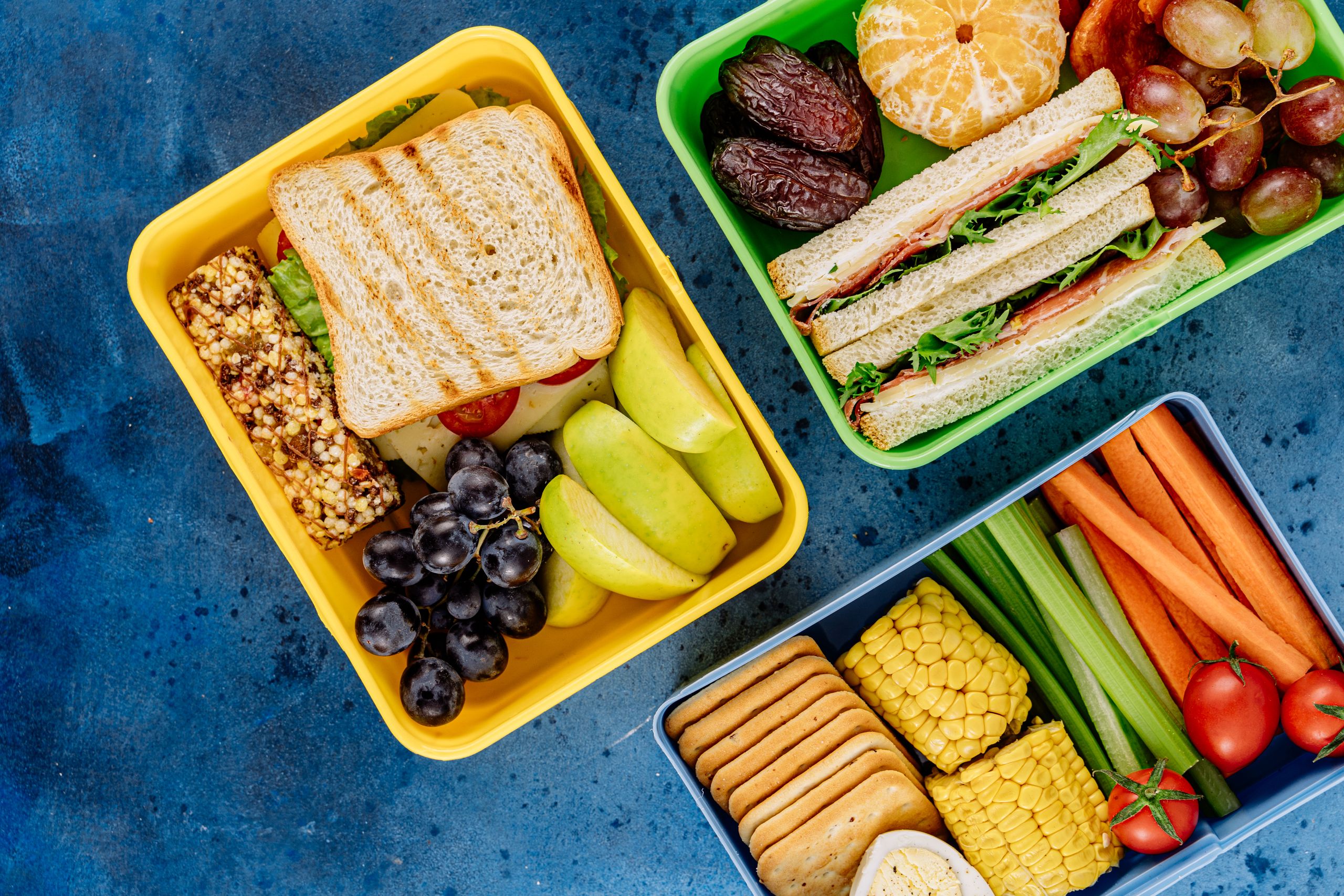 Colorful lunch boxes filled with sandwiches, fruits, and vegetables for a healthy meal.