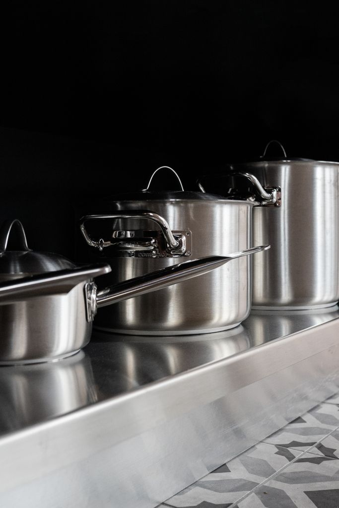 Stainless steel pots and pans displayed on a geometric counter, ideal for searing, deglazing, and contemporary kitchens