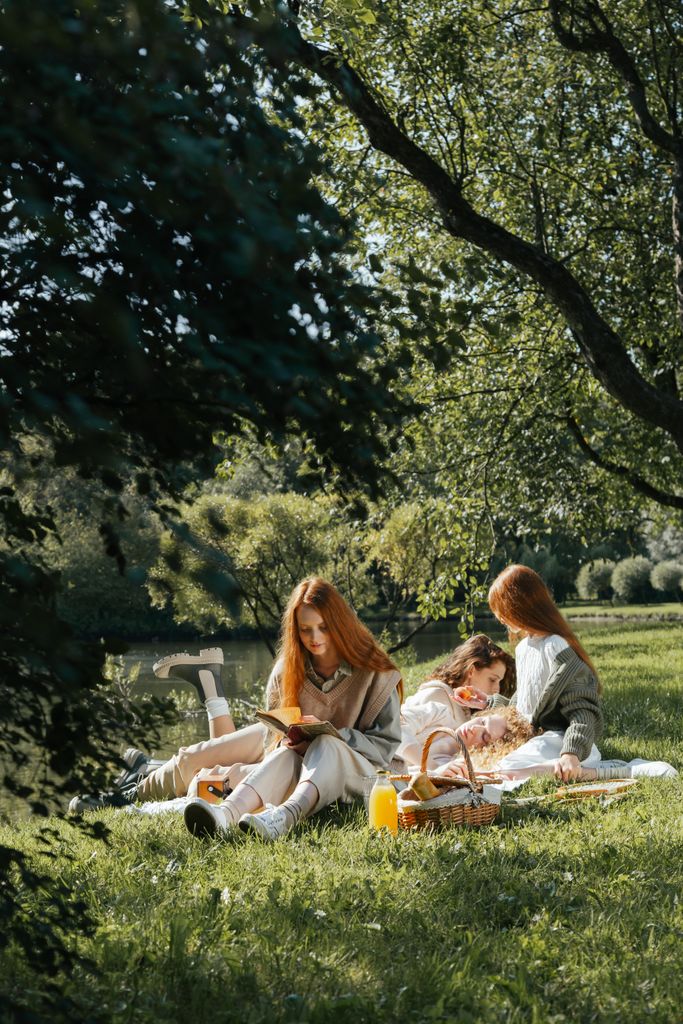 Women enjoying a peaceful picnic outdoors under lush trees.