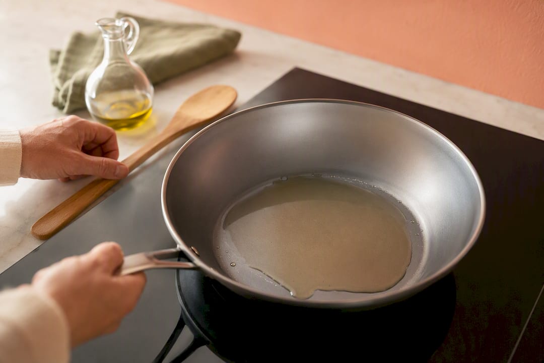Hands gradually preheating an uncoated pan